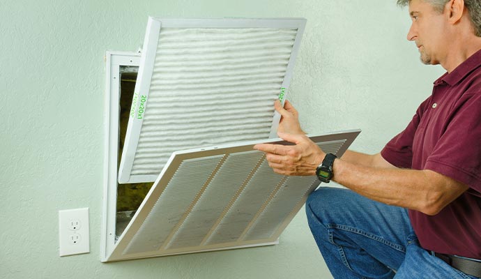 A person removing a white pleated air filter