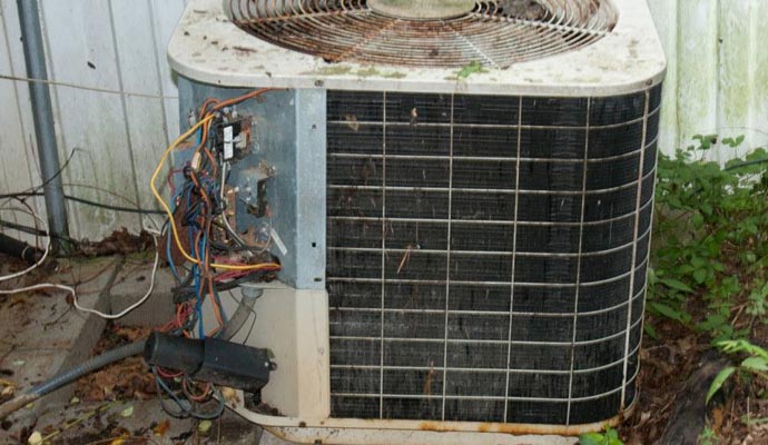 Damaged outdoor AC unit with exposed wires