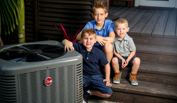 children sitting with a new Rheem HVAC unit