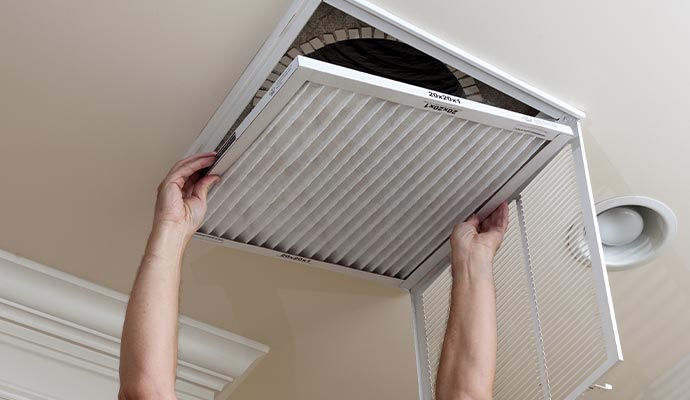 Person removing air filter from ceiling vent